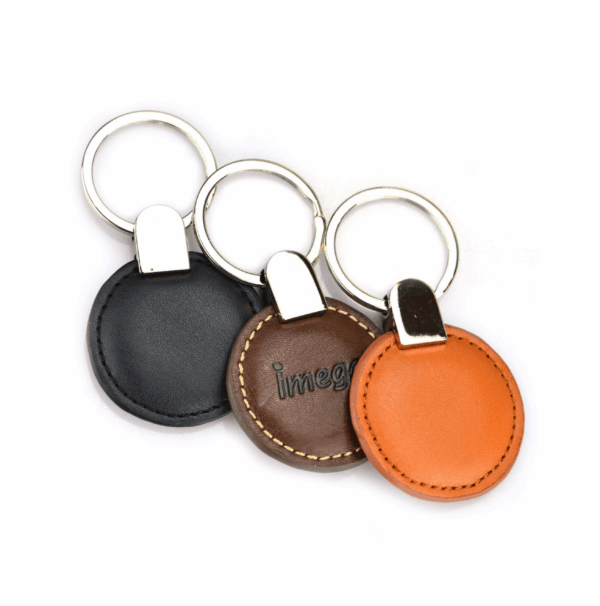 Round PU keychains in black, brown, and orange with visible stitching